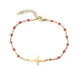 Bracelet croix en métal doré avec entrelacement de perles de couleur rouge